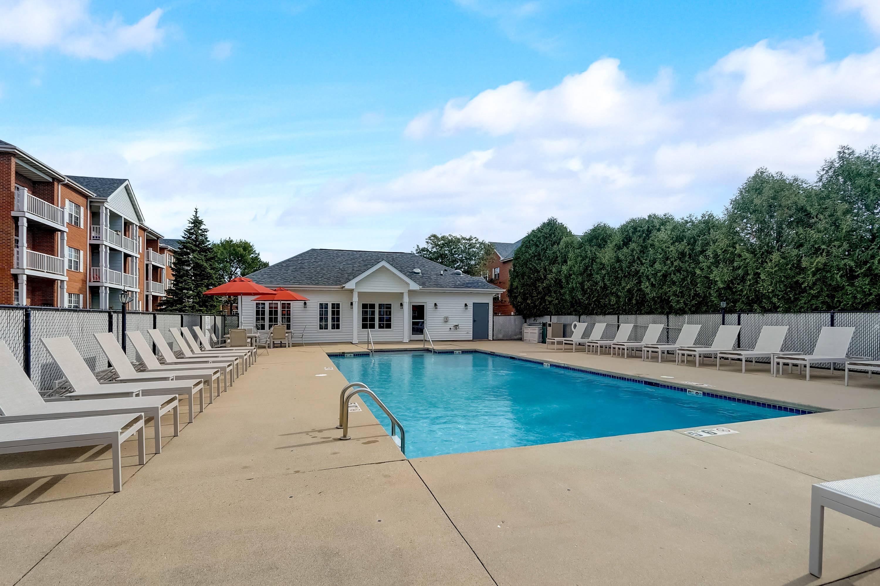 A pool surrounded by sun loungers and a building in the background.